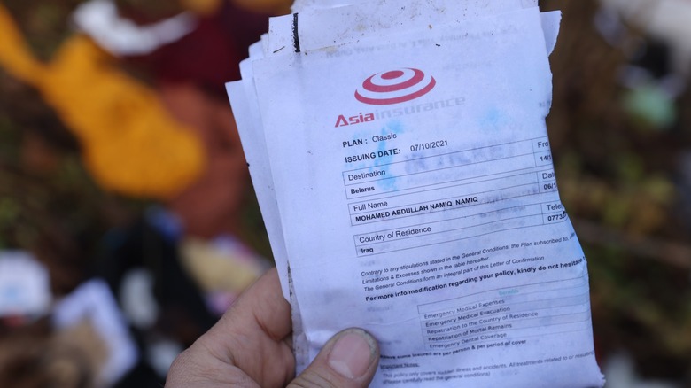 A hand holding travel insurance documents