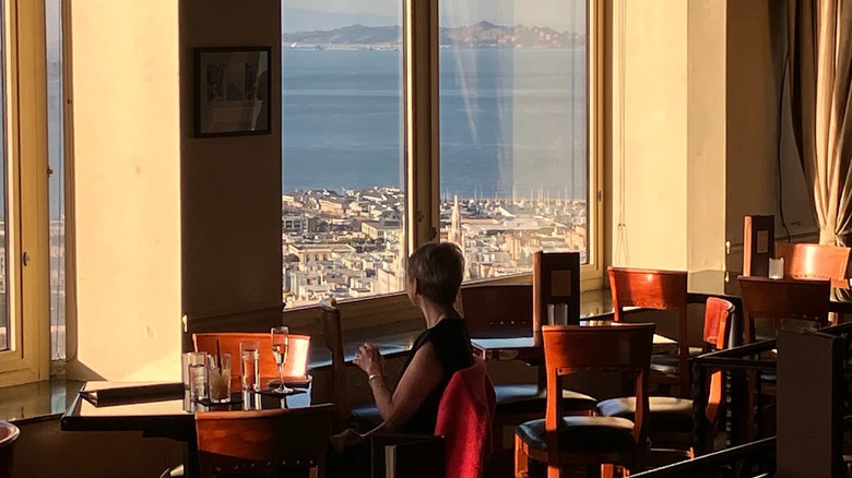 A woman sits at a table at Top of the Mark bar, overlooking downtown San Francisco