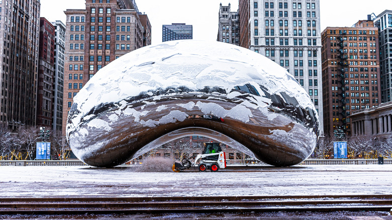 Tractor is shoveling snow near Cloud Gate or the bean at Millennium Park in the Loop community area of Chicago after snow storm.