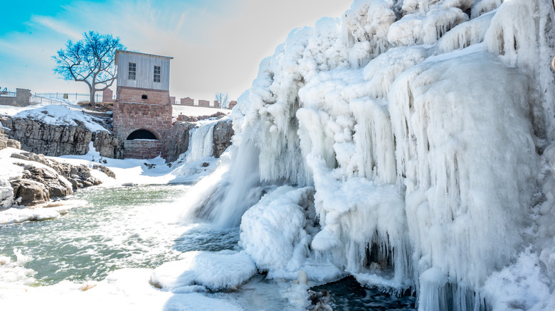 Sioux Falls Park waterfall with ice and snow. Cascading snowmelt water pouring over the top into a pool of standing water. High quality photo