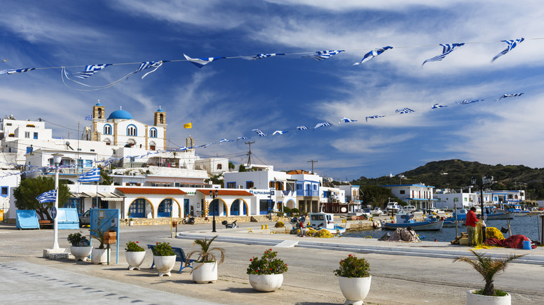 white washed town, blue dome church, as seen from the harbor, Greek flags flying in the wind