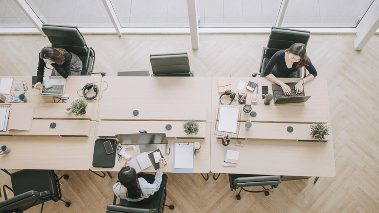 Three women working in an open-plan office and leaving a large gap between themselves and their fellow workers