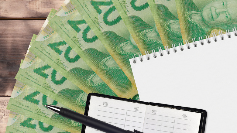 20 Canadian dollars bills fan and notepad with contact book and black pen