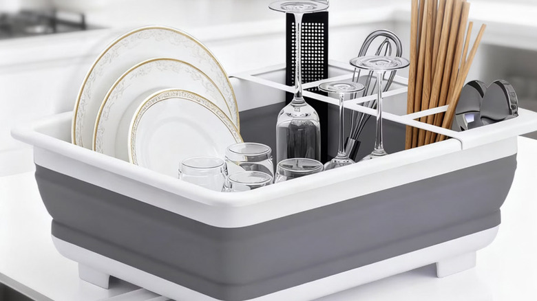 View of dishes drying in collapsible dish drying rack on white counter