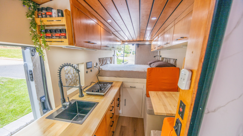 Interior view of an RV with a warm and cozy design, featuring wooden accents and soft lighting.