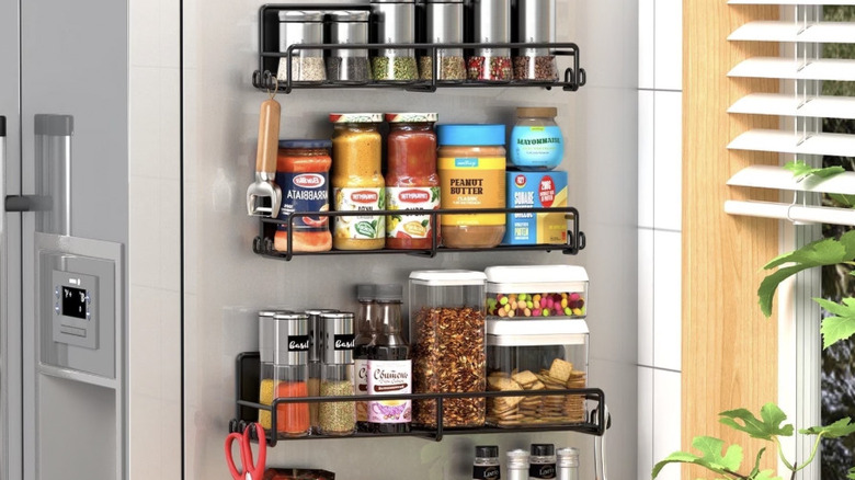 View of magnetic spice racks holding spice canisters and food items attached to the side of a refrigerator