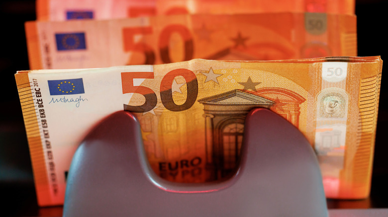 An ATM dispensing a large amount of 50 euro banknotes