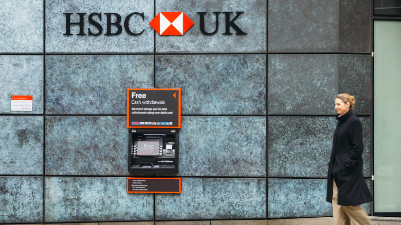 A woman walks past an Automatic Teller Machine from the HSBC bank advertising free cash withdrawals