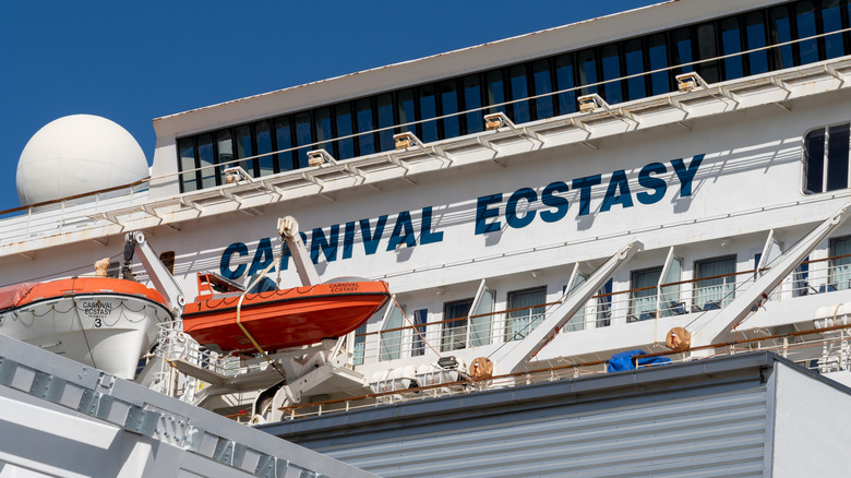 View of the side of the Carnival Ecstasy cruise ship with orange life boats in the foreground
