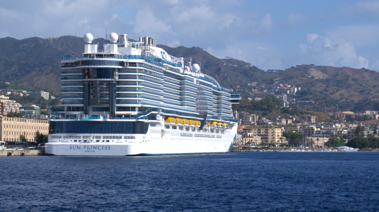 Princess Cruise Lines ship in European port with mountains and buildings in the background