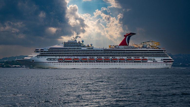 View of the Carnival Sunshine headed to sea from the Port of New York with clouds and a burst of sunlight in the background