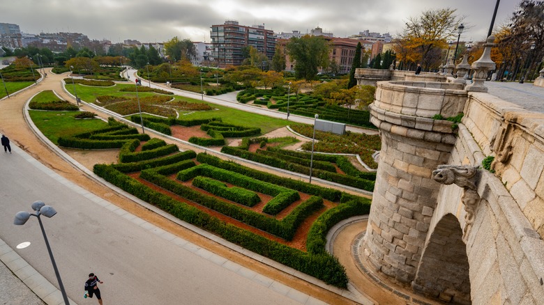 View over Madrid Rio park with an old bridge, gardens and pedestrian path on a cloudy day