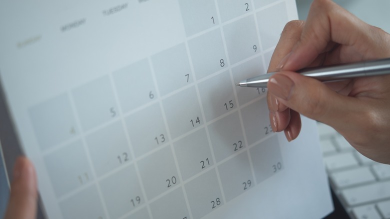 Someone's hand writing on a calendar