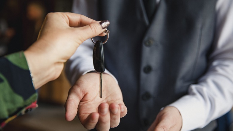 A hand passing a key to the valet driver