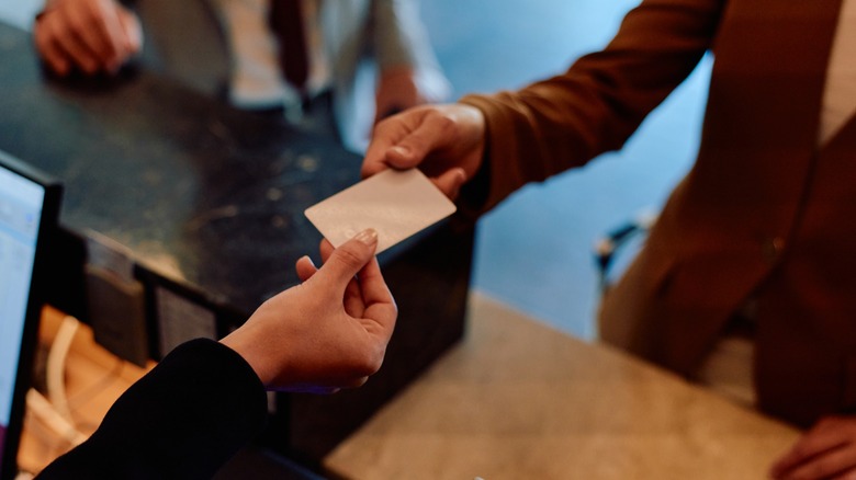 A hotel guest handing a front desk worker their credit card