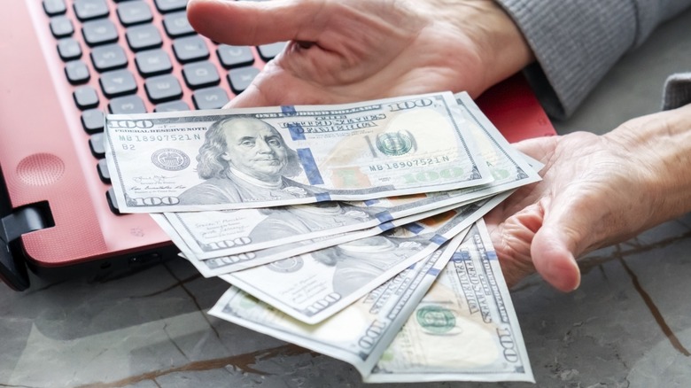 A person holding hundred dollar bills