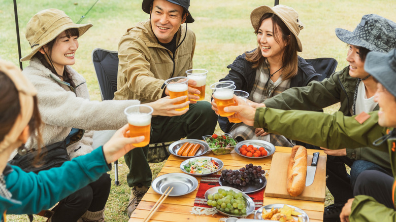 Asian men and women enjoying group camping with food on a table