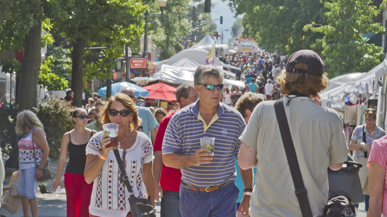 A couple walking with beer cups in hand during a street festival in Asheville