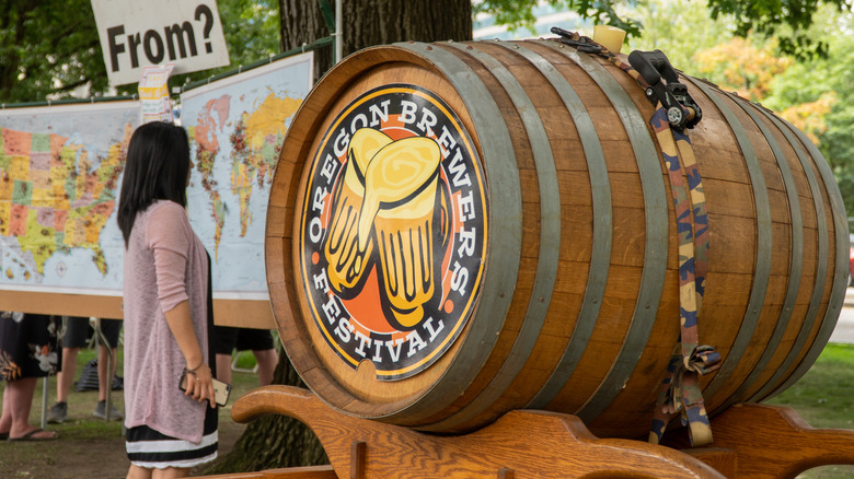 A woman standing in front of a large barrel at Oregon Brewers Festival in Portland