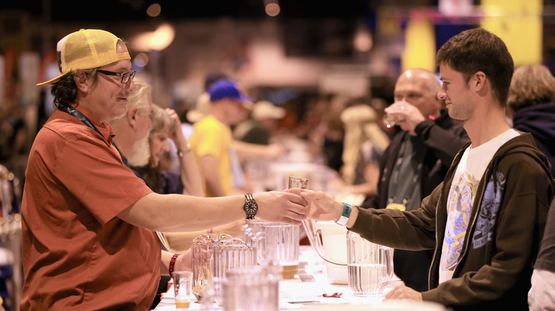 an handing another man a glass of beer at the Great American Beer Festival