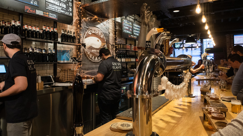 Interior of Goose Island Brewing Company showing bartenders and patrons and a large beer tap