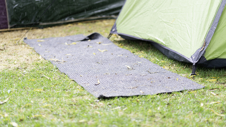 A mat on the ground outside of a tent