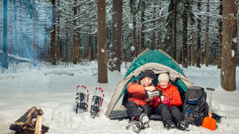 A couple camping amid winter snow