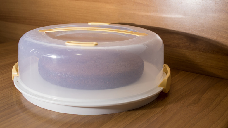 A clear plastic cake container with a chocolate cake inside