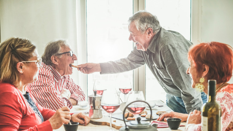Seniors drinking wine and having a conversation at a dinner table
