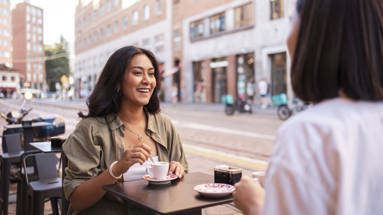 Two women drinking coffee and talking at a cafe