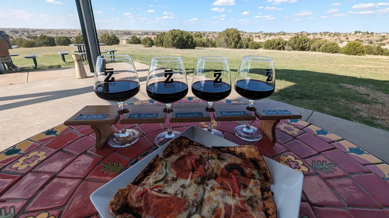A flight of red wines on a tile table overlooking Texas Panhandle grasslands at Bar Z Winery