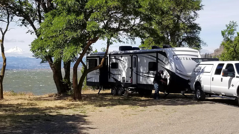 A camper parked beneath some trees along the Columbia River at Avery Recreation Area with Mount Hood in the distance