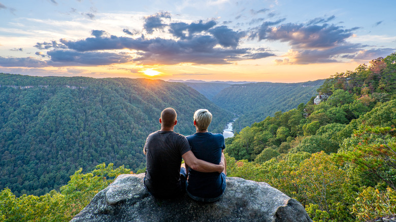 Couple enjoying a vibrant sunset view from Beauty Mountain in New River Gorge National Park