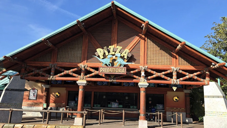 Exterior view of Pizza Predattoria with dinosaur-themed signage at Universal Islands of Adventure on a sunny day.