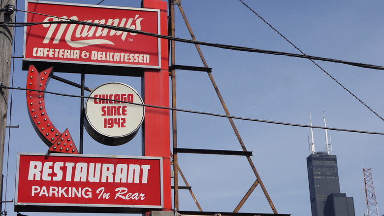The red sign on the roof of Manny's Cafeteria with blue sky in the background