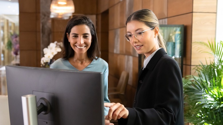 Front desk employee helping another woman check into a hotel