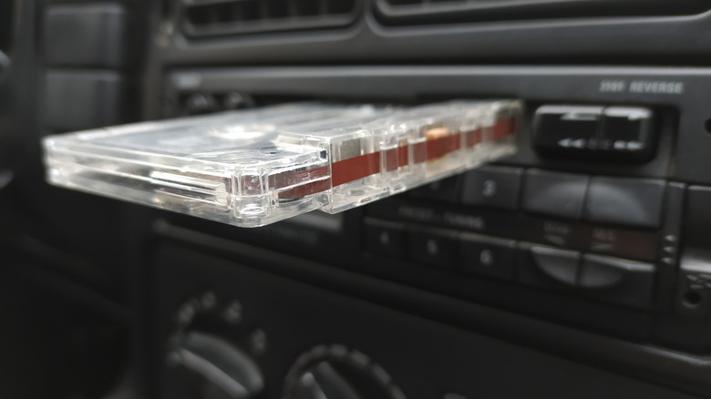 A cassette tape half in and half out of a vintage car stereo