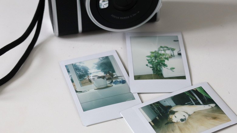 A Polaroid camera rests nearby, with several photos scattered nearby