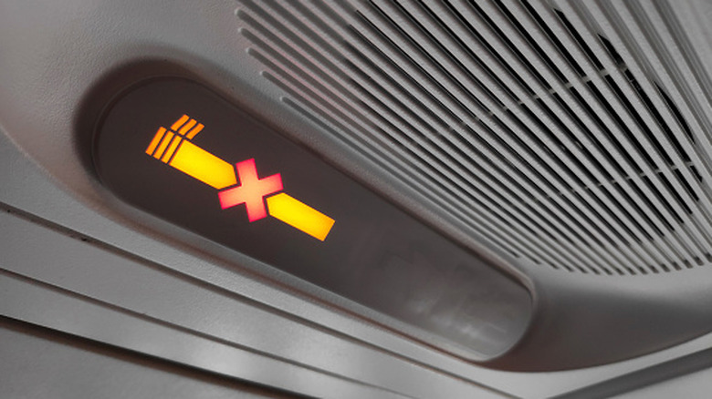 No smoking sign on the overhead information panel in the airplane above the passenger seat