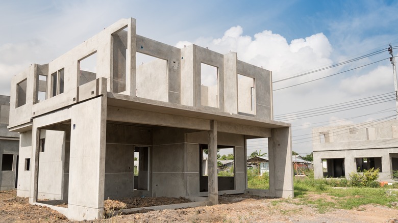 A partially-completed concrete structure on a sandy, grassy lot