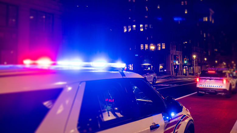 Two police cars moving along a city road with lights flashing