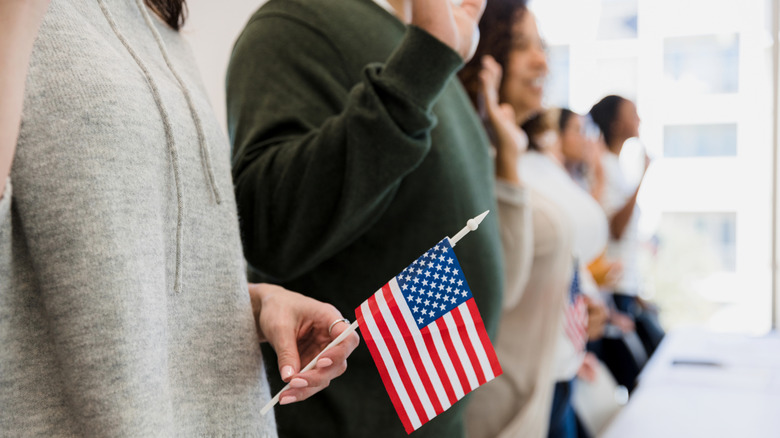 People holding up a hand while holding an American flag