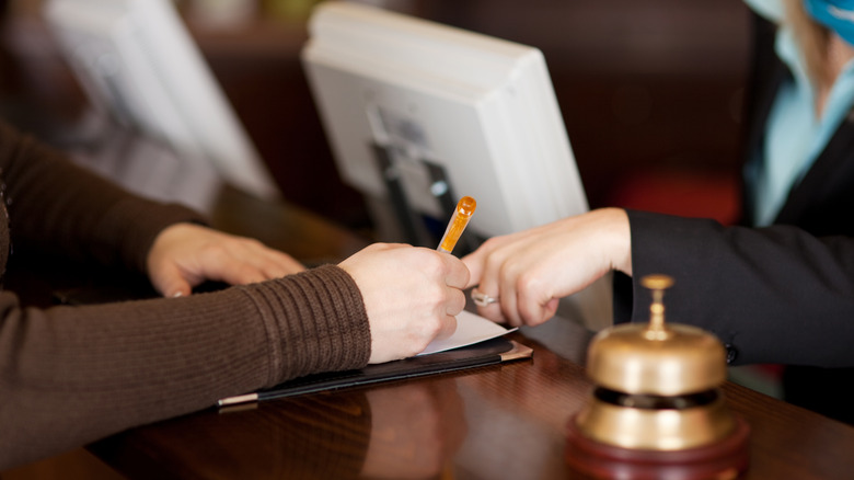 Hotel employee helping guest fill out a form during check-in