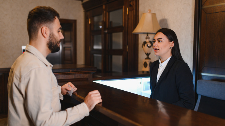 Hotel staff talking to male guest at the reception desk