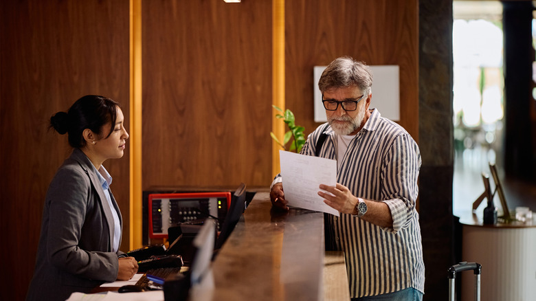 Man in striped shirt reading a form during hotel check-in