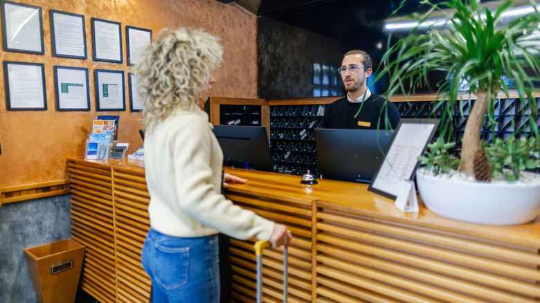 Curly haired woman talking to hotel staff at check-in