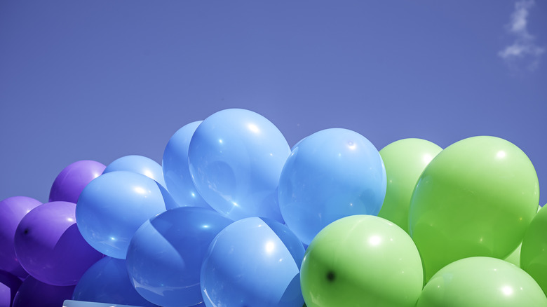Blue, green, and purple balloons against a blue sky