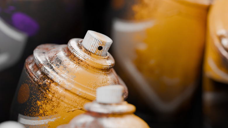 Graffiti spray can aerosol bottles in a pile with splattered paint