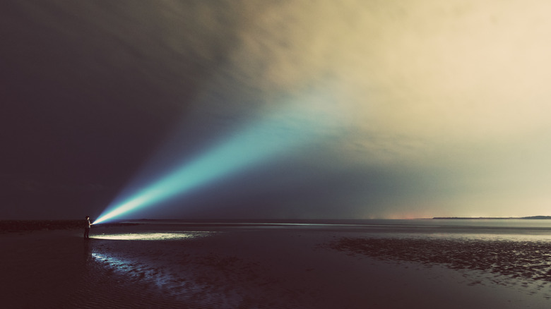 A man shines bright spotlight into overcast skies