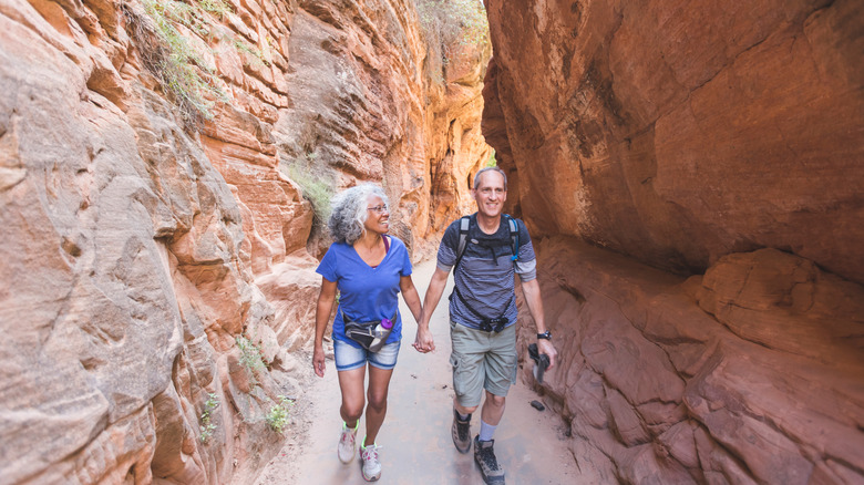 A middle-aged couple hikes through a majestic Utah canyon